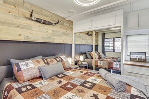 A bedroom with a wooden headboard, a quilted bedspread, a mirror, and a bedside table with a lamp. - Dock & Beach Access: Cozy Lake Havasu City Home! (Lake Havasu City)