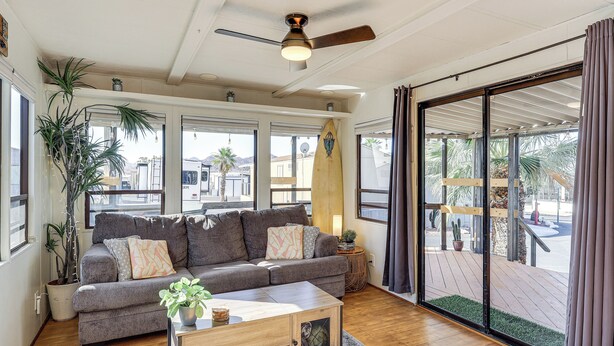 A living room with a grey sofa, wooden coffee table, and a ceiling fan.