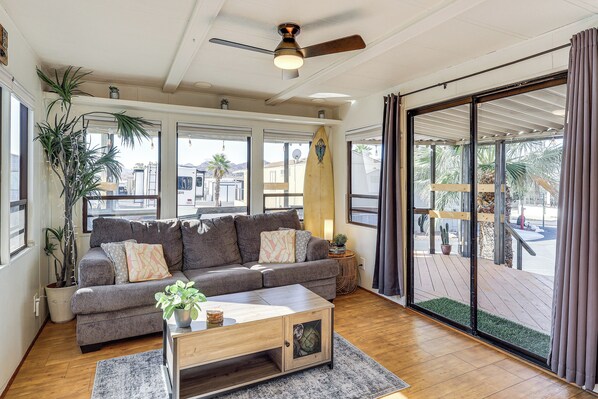 A living room with a grey sofa, wooden coffee table, and a ceiling fan. - Dock & Beach Access: Cozy Lake Havasu City Home! (Lake Havasu City)