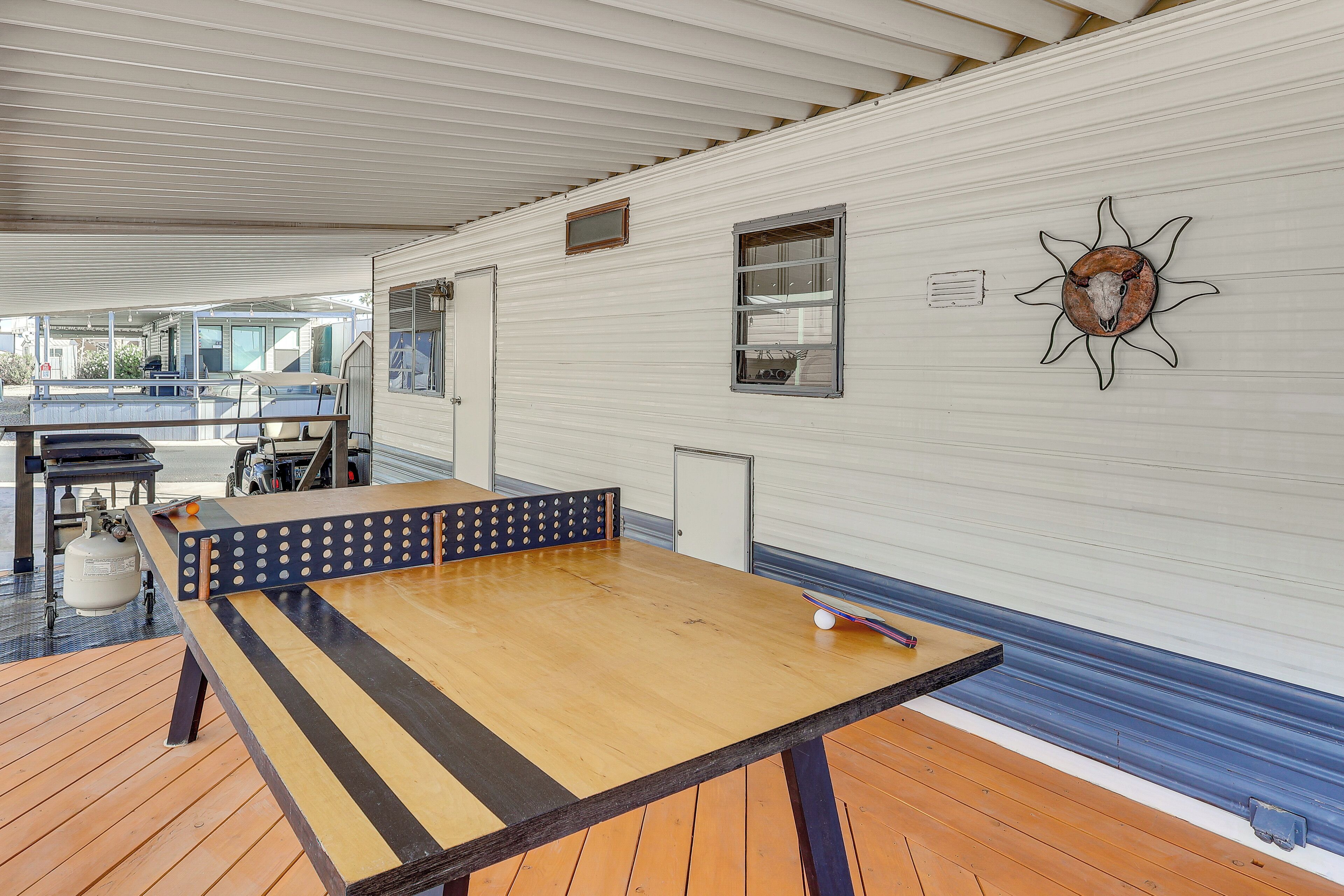 A ping pong table, a gas cylinder, and a sun-shaped decoration on a white wall.