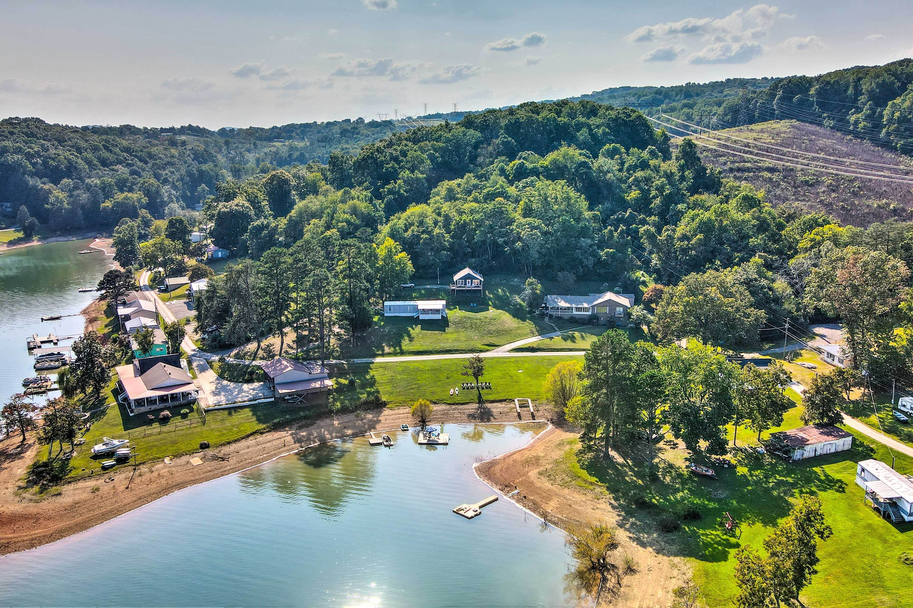 An aerial view of a lakeside property with multiple houses, boats, and a dock.