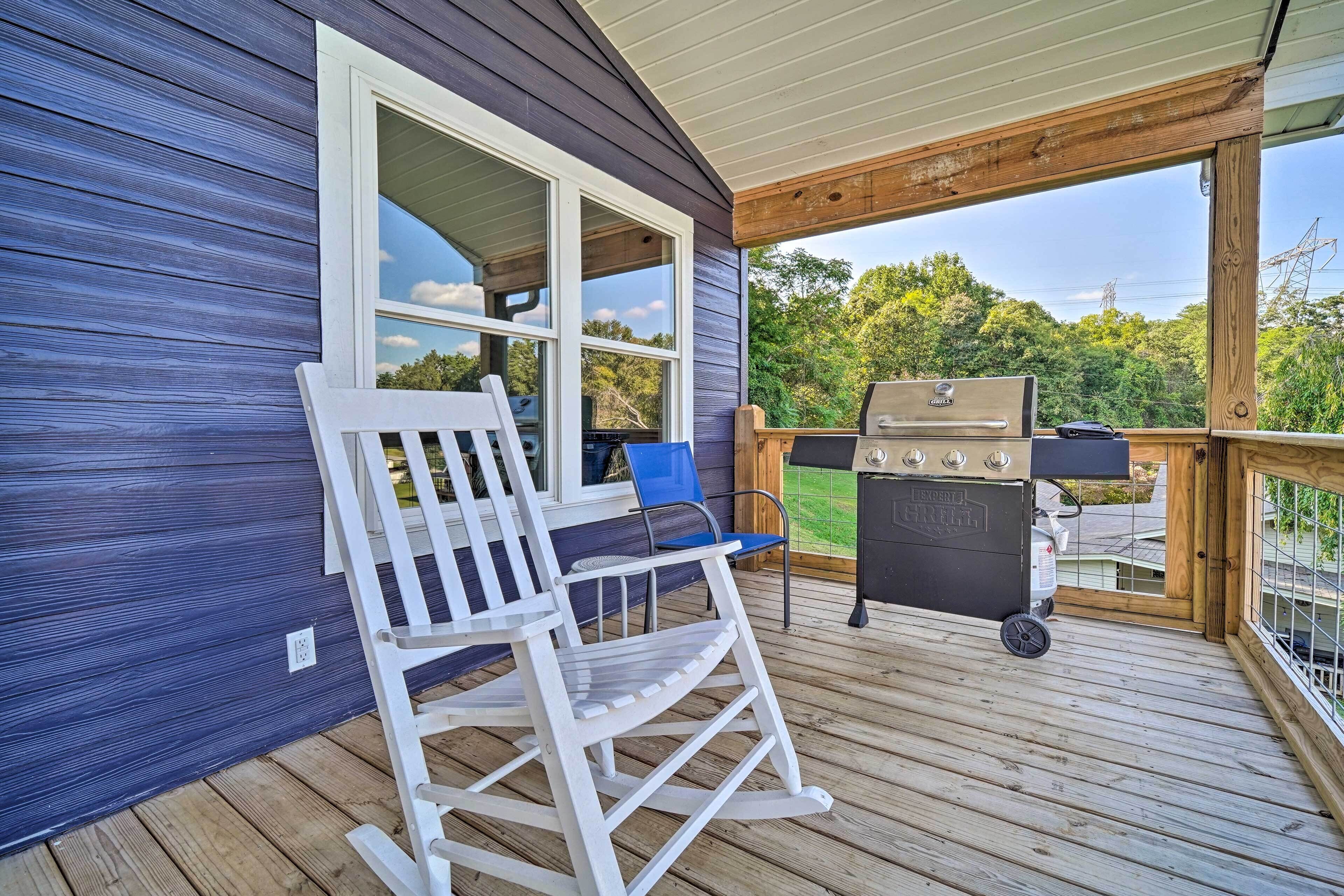 Eine Holzterrasse mit Schaukelstuhl und Grill.
