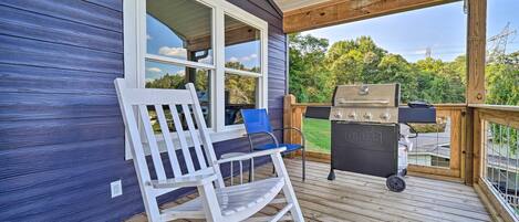 Eine Holzterrasse mit Schaukelstuhl und Grill.