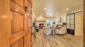 A spacious living room with a fireplace, wooden flooring, and a large wooden door. - Sedona Condo w/ Pool, Hot Tub, & Pickleball! (Sedona)