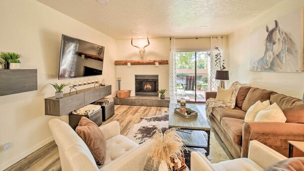 A modern living room with a fireplace, comfortable seating, a mounted TV, and a large painting. - Sedona Condo w/ Pool, Hot Tub, & Pickleball! (Sedona)