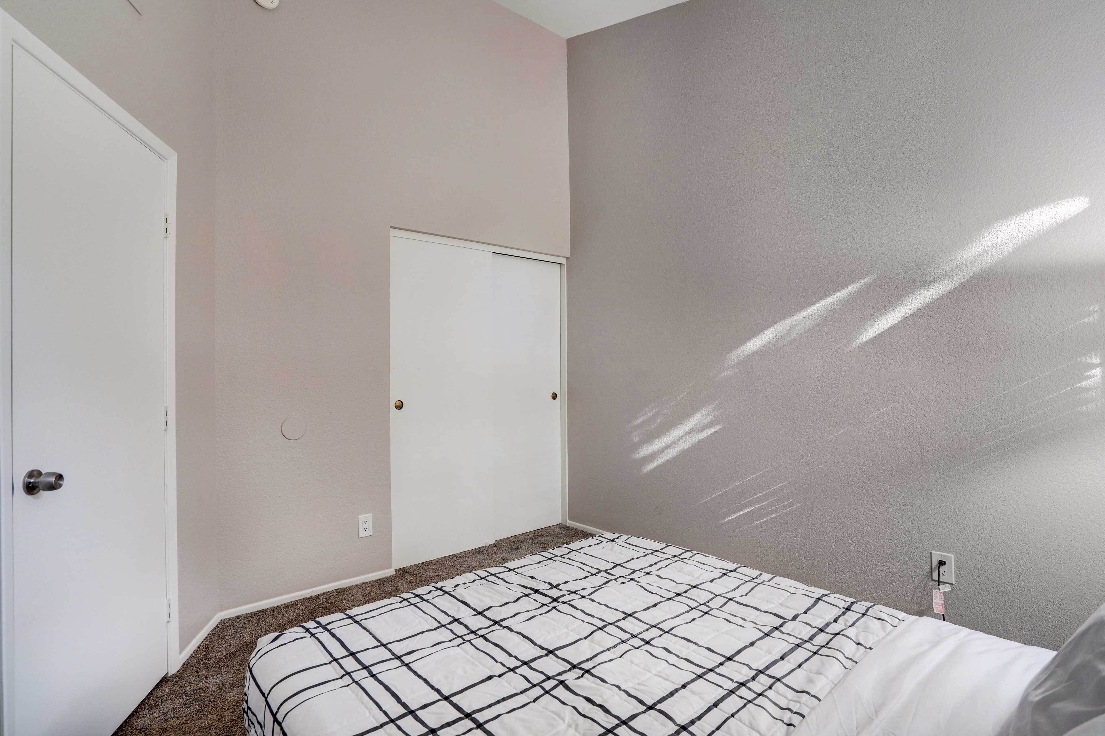 Ein Schlafzimmer mit einem Bett, einer Tür und einer Wand mit Lichtschalter.