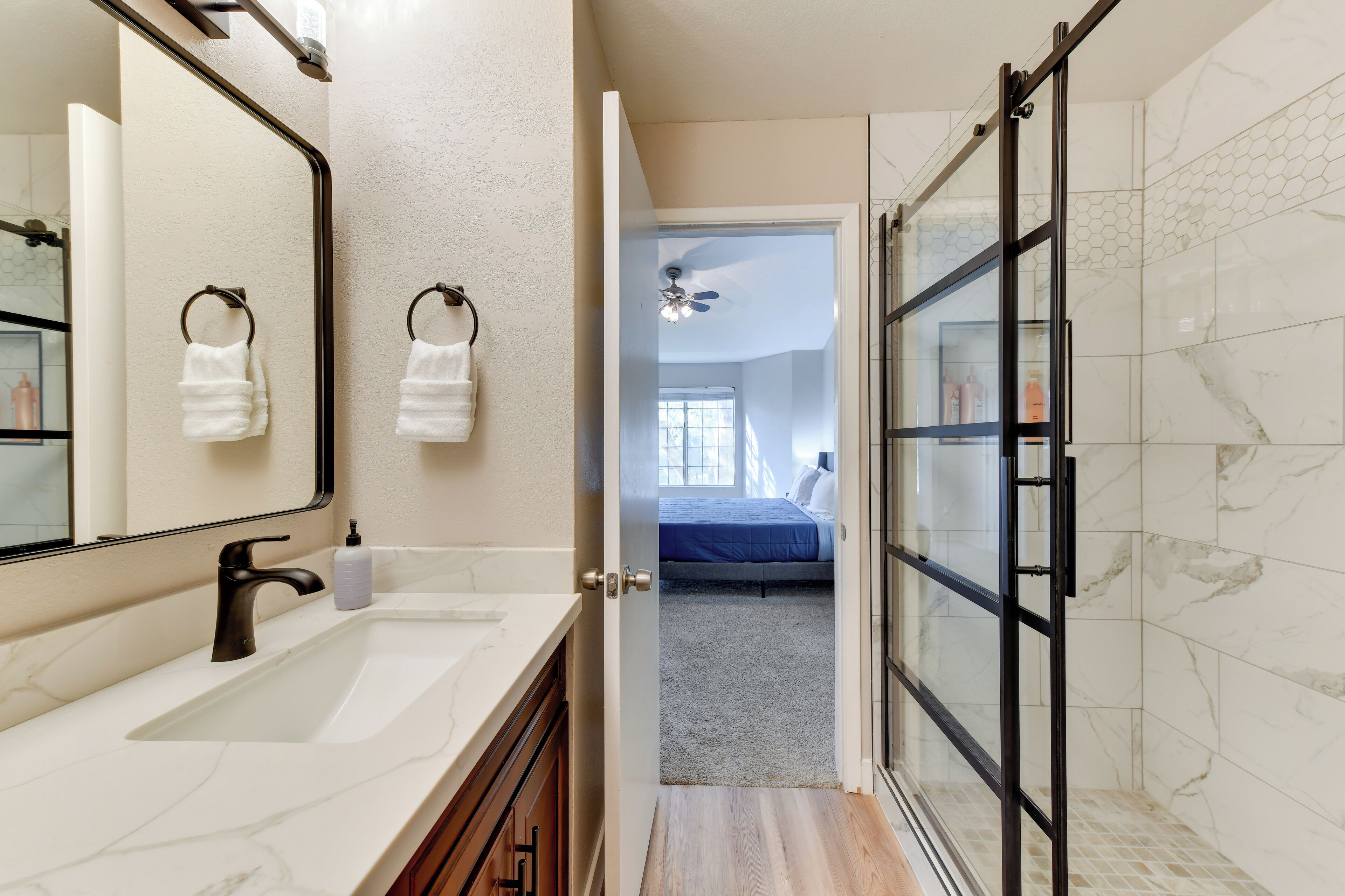 Une salle de bain moderne avec un grand miroir, un lavabo et un espace douche.