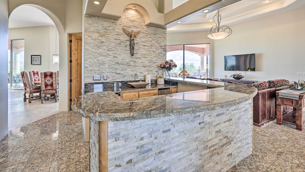 A spacious kitchen with a large island, stone backsplash, and modern lighting fixtures. - Backyard Oasis! Mtn-view Family Gem in Scottsdale (Scottsdale)