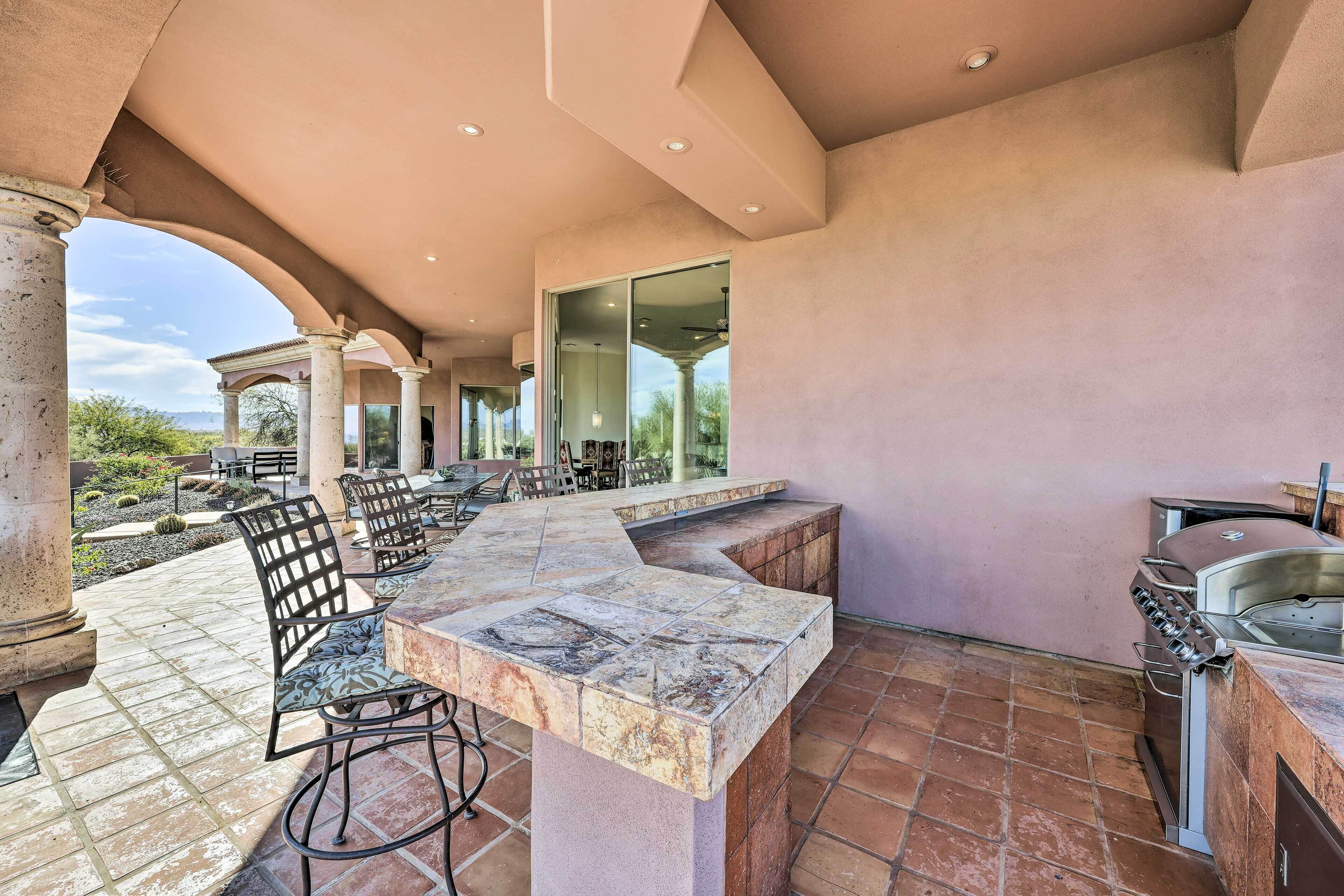 An outdoor patio with a stone bar, seating, and a grill area.