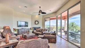 A spacious living room with a fireplace, comfortable seating, and a large sliding glass door leading to an outdoor patio. - Backyard Oasis! Mtn-view Family Gem in Scottsdale (Scottsdale)