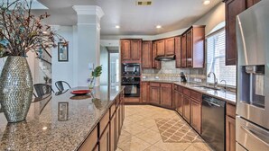 Una cocina moderna con encimeras de granito, electrodomésticos de acero inoxidable y muebles de madera.