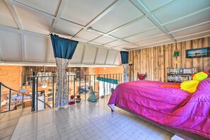 Een kamer met een groot bed, een houten wand, een balkon en een boekenkast.