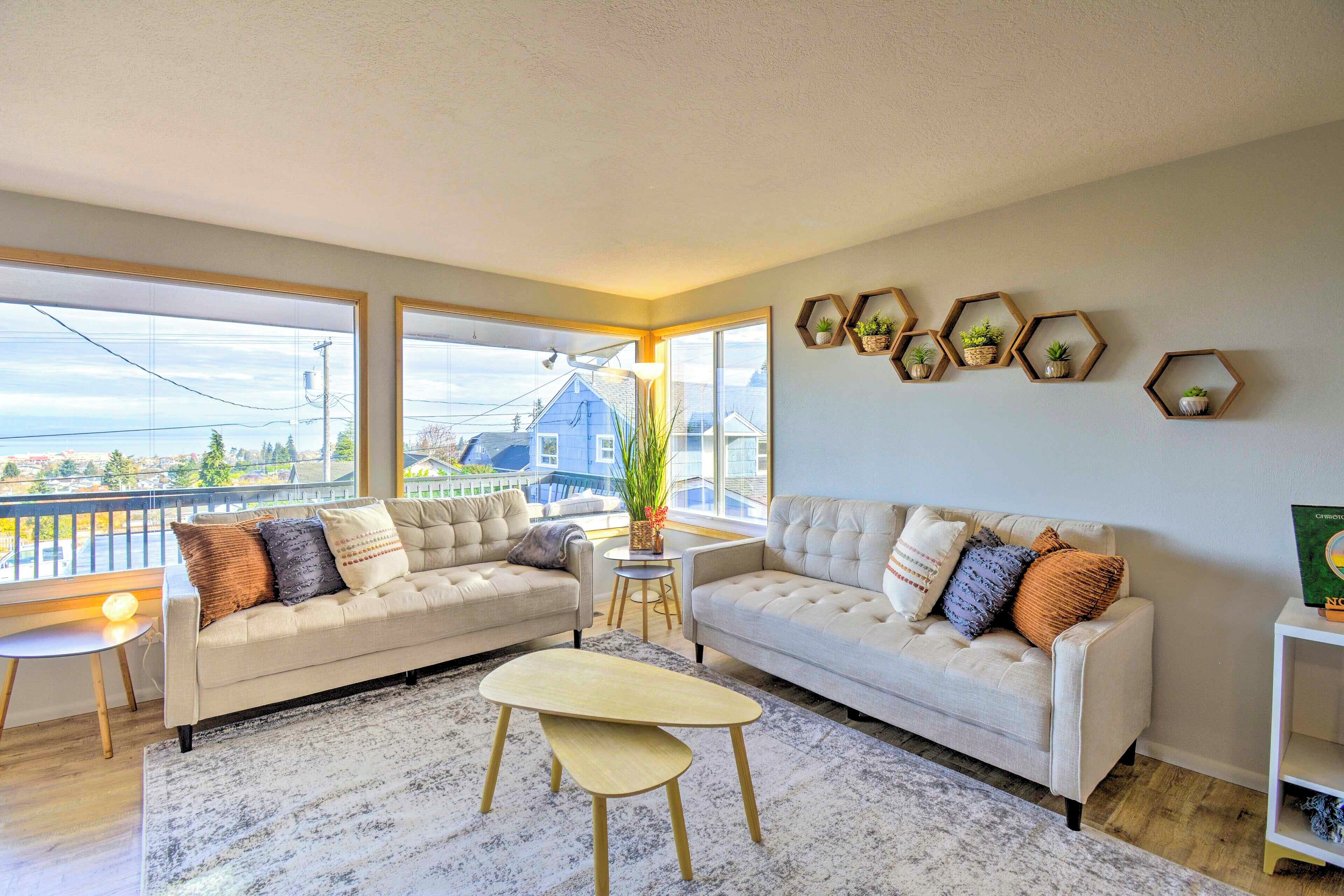 A modern living room with two sofas, a coffee table, and a view of the city through large windows.