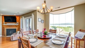 A dining area with a large table set for six, a fireplace, and a view of the outdoors.
