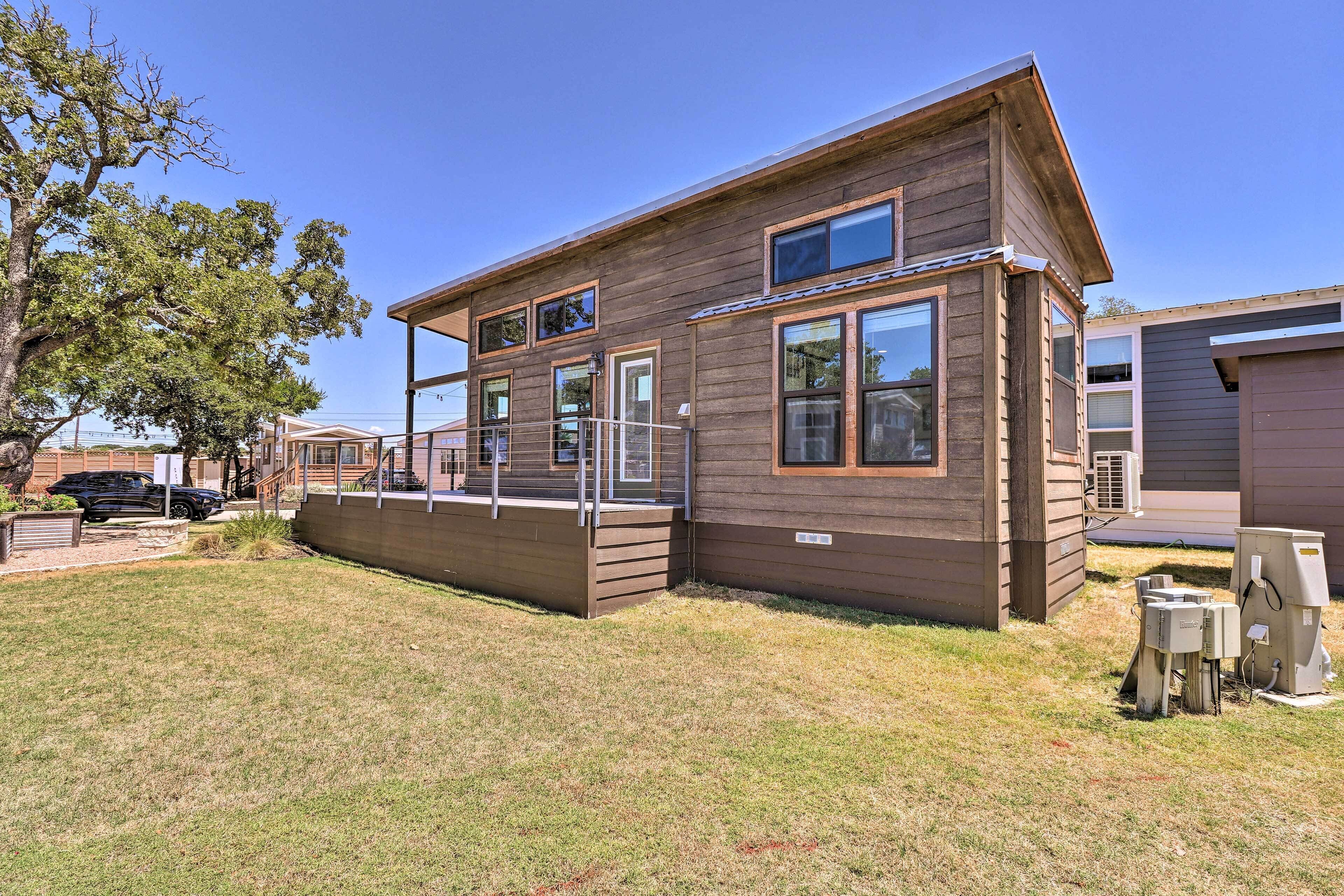 A two-story wooden house with a covered porch, a fenced yard, and a black car parked nearby.