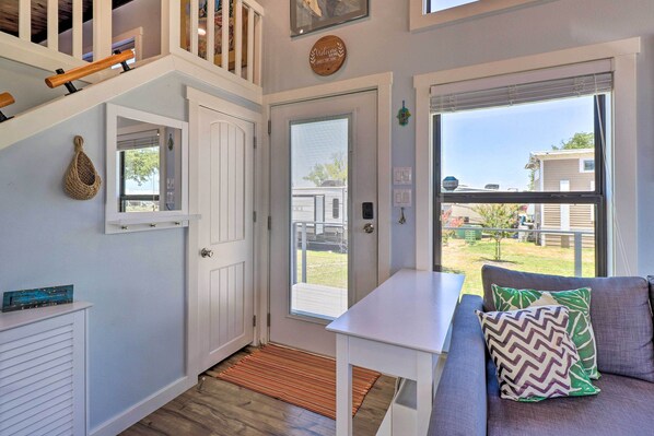 A cozy interior with a white door, a small table, and a gray sofa with patterned cushions. - Upscale Tiny Home - Boho-chic Austin Getaway! (Austin)