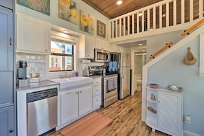 A modern kitchen with white cabinets, stainless steel appliances, and a wooden staircase. - Upscale Tiny Home - Boho-chic Austin Getaway! (Austin)