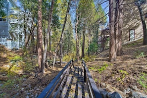 Un puente de madera en una zona boscosa, con edificios al fondo.