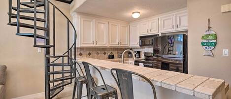 A kitchen with a central island, a spiral staircase, and white cabinets.