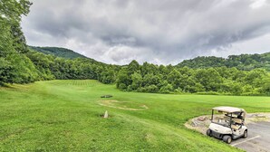 Un campo de golf con un carrito de golf estacionado cerca del borde de la carretera.