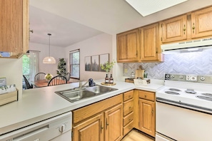A modern kitchen with wooden cabinets, a white countertop, stainless steel sink, and a built-in oven. - Maggie Valley Townhome In Smoky Mountain Foothills (Waynesville)