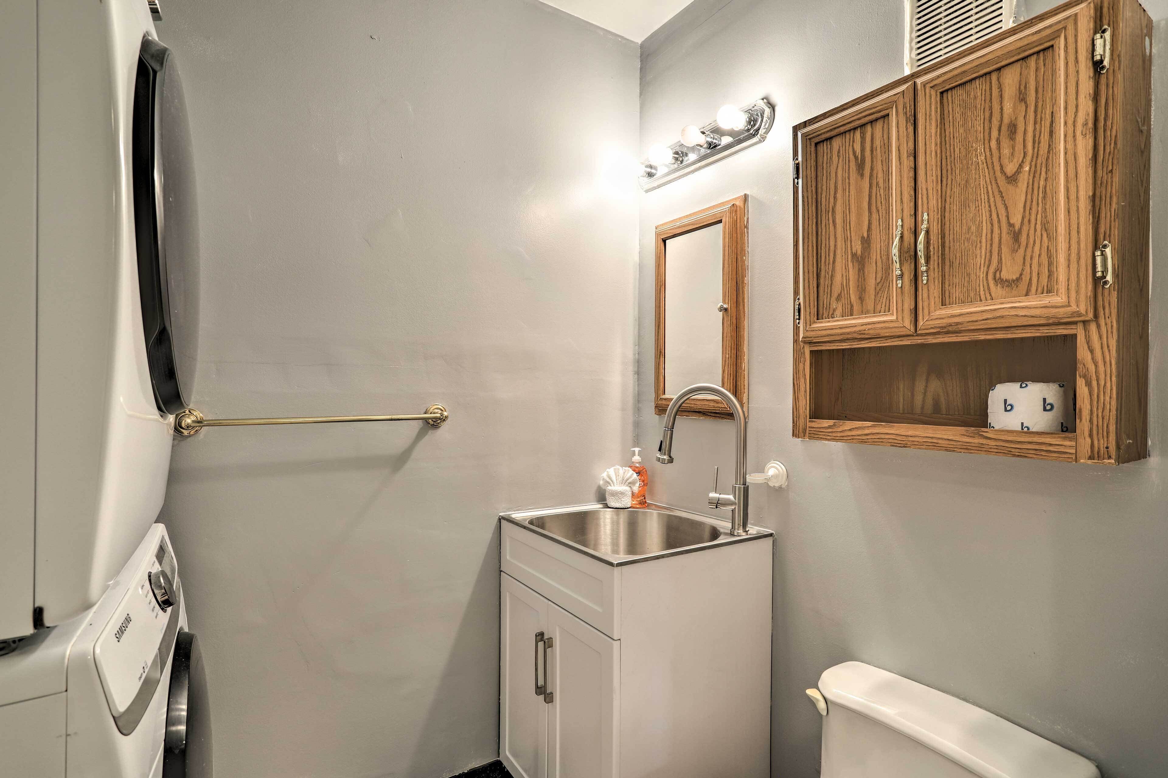 A compact bathroom with a built-in sink, a toilet, and a wooden cabinet above the sink.