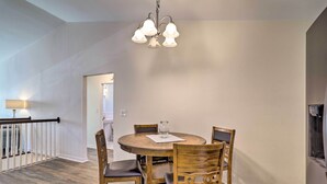 A dining area with a round wooden table, four chairs, and a chandelier. - St Petersburg Hideaway w/ Fire Pit & Grill! (St. Petersburg)