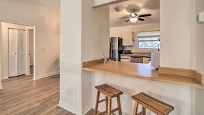 A modern kitchen with a wooden countertop, two stools, a ceiling fan, and a view of the adjacent living area. - St Petersburg Hideaway w/ Fire Pit & Grill! (St. Petersburg)
