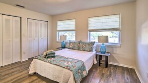 A bedroom with a bed, two windows with blinds, a nightstand, and a lamp. - St Petersburg Hideaway w/ Fire Pit & Grill! (St. Petersburg)