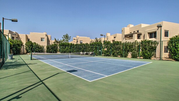 An outdoor tennis court surrounded by buildings and greenery. - Modern Scottsdale Condo ~ 10 Mi to Old Town! (Scottsdale)