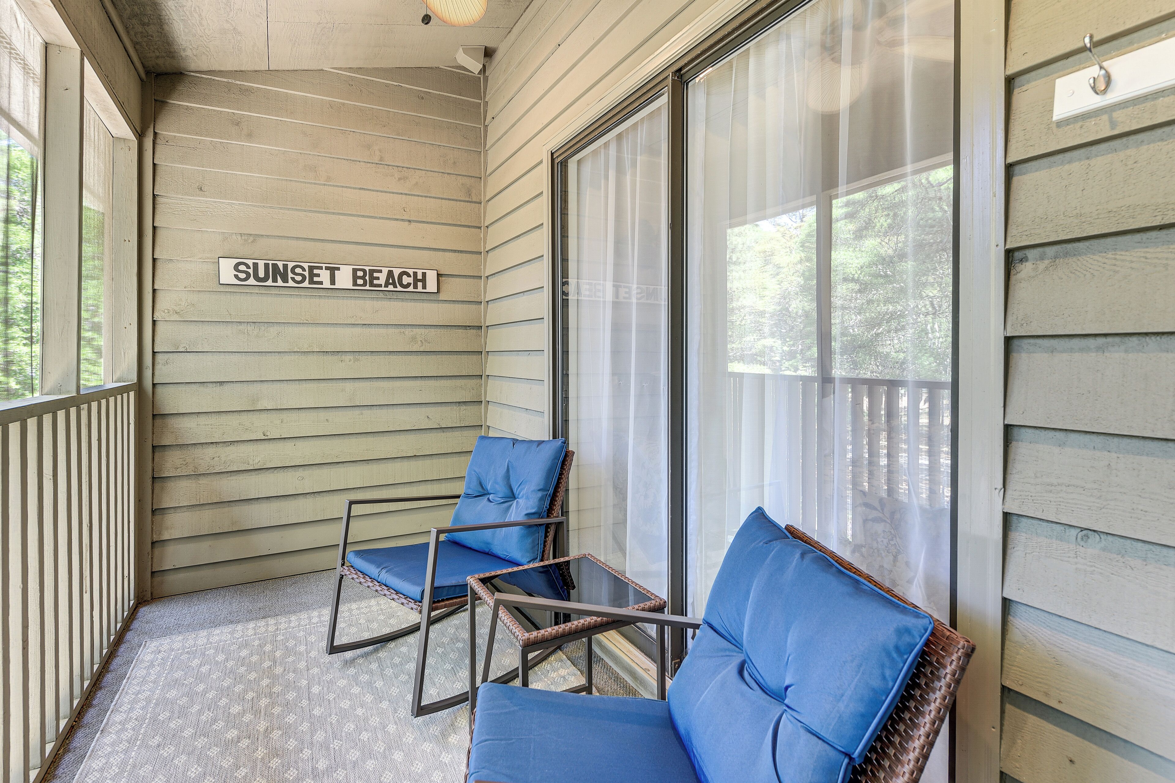 Eine Veranda mit zwei Korbstühlen und einem Schild mit der Aufschrift 'SUNSET BEACH'.