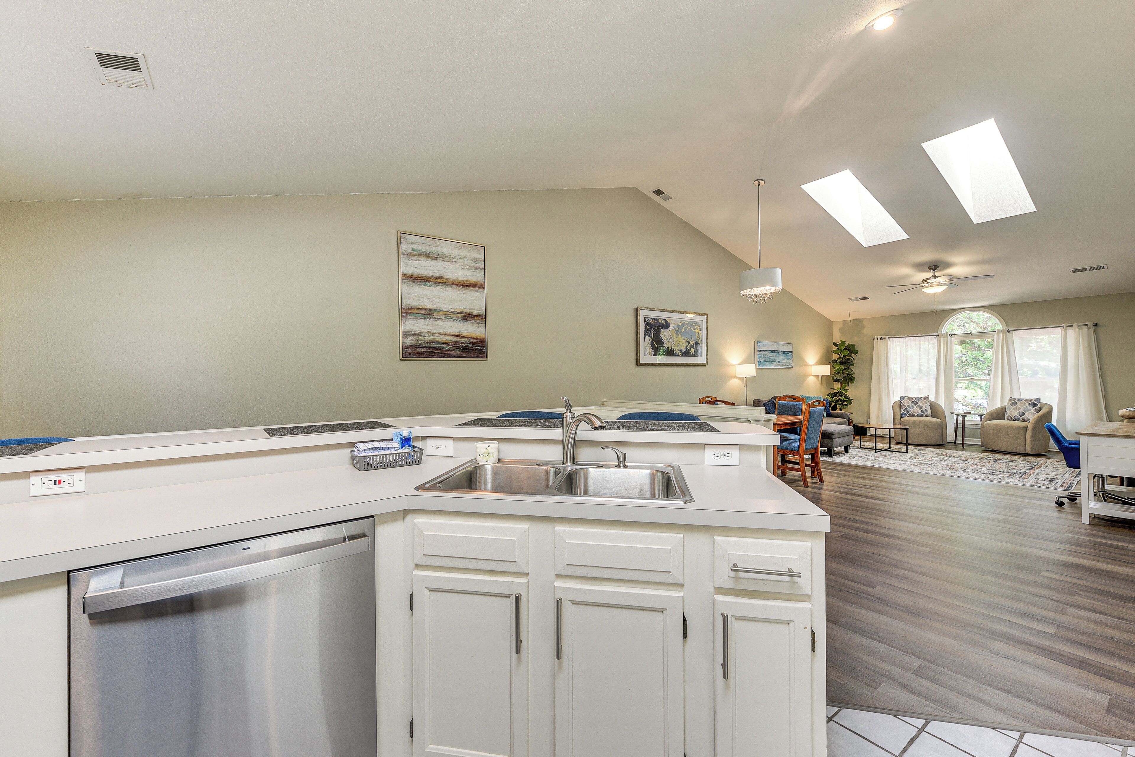 A modern kitchen with a dishwasher, a sink, and a dining area with a table and chairs.