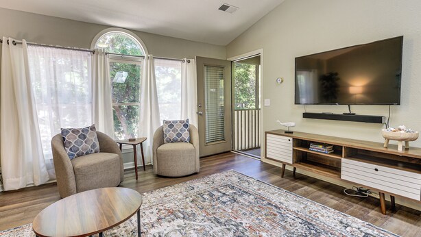 A living room with a flat-screen TV, two armchairs, a coffee table, and a wooden entertainment unit. - Resort Condo ~ 2 Mi to Sunset Beach Seashore! (Sunset Beach)