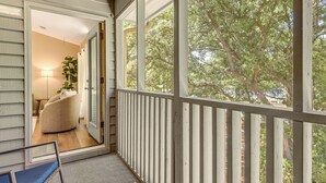 A balcony with a wooden railing, a chair, and a view of trees. - Resort Condo ~ 2 Mi to Sunset Beach Seashore! (Sunset Beach)