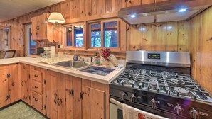 A kitchen with wooden cabinets, a stainless steel stove, and a window overlooking greenery. - Riverfront Escape w/ Dock: 19 Mi to Saratoga! (Lake Luzerne)