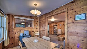 A wooden interior with a dining table, chairs, a ceiling light, and a window with curtains. - Riverfront Escape w/ Dock: 19 Mi to Saratoga! (Lake Luzerne)