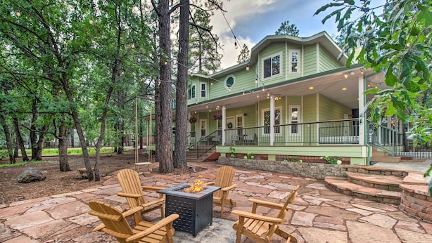 A green house with a porch, stone patio, and Adirondack chairs. - 2 Mi to Lake: Marvelous Pinetop Home w/ Fireplaces (Pinetop)
