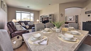 A dining area with a marble table set for four, surrounded by grey chairs.