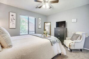 A bedroom with a large bed, a dresser, a chair, a ceiling fan, and a TV. - 1/2 Mi to Lake: Family Home w/ Hot Tub in Goodyear (Goodyear)