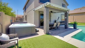 A house with a covered patio, a hot tub, and a pool.