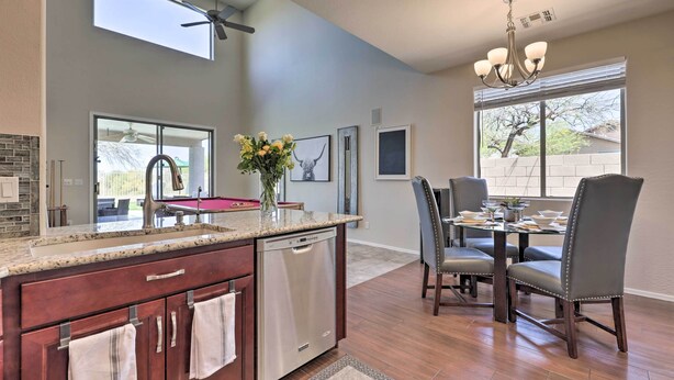 A modern kitchen with a dishwasher, granite countertop, and a dining area with a table and chairs.