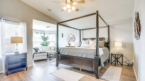 A four-poster bed with a wooden frame, a bedside table with a lamp, and a small rug on a wooden floor.
