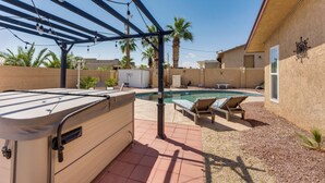 Ein Garten mit Whirlpool, Pool und Liegestühlen.