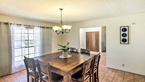 Ein Esszimmer mit Holztisch, sechs Stühlen, einer Chandelier und einem Blumentopf.