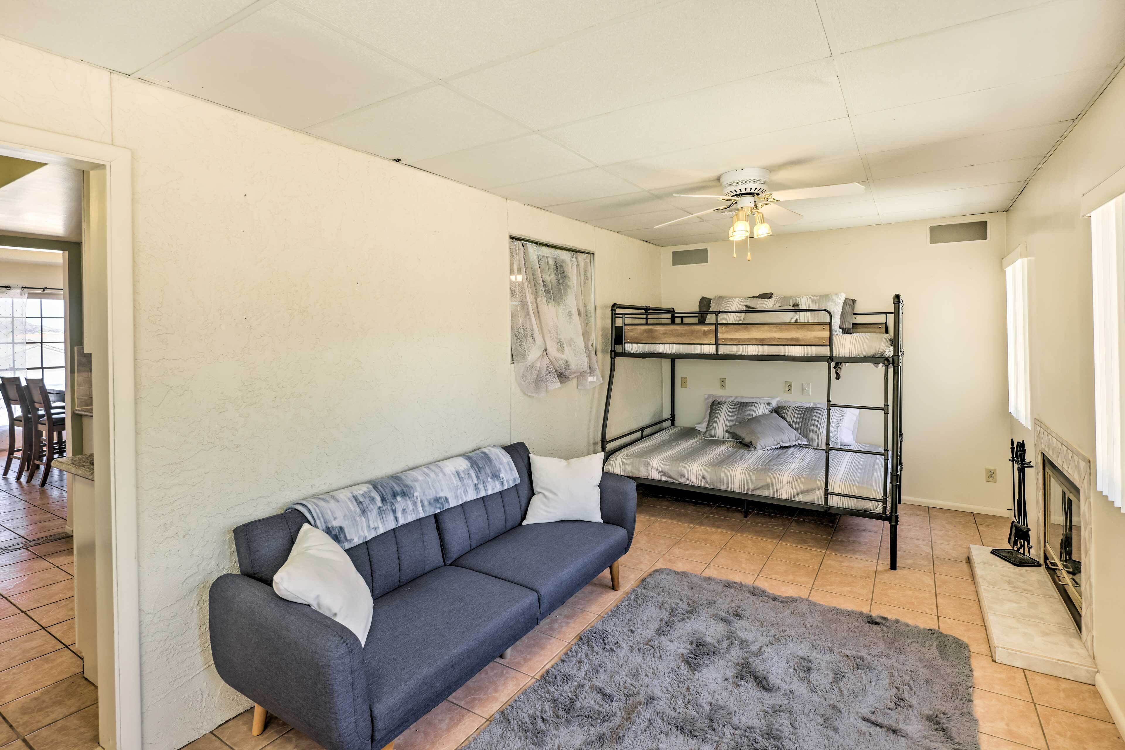 Et værelse med sofa, køjeseng, ventilator og pejs.