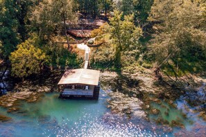 A floating house with a wooden deck and a small boat dock. - Riverfront Retreat w/ Fire Pit: Fish & Hike! (Heber Springs)