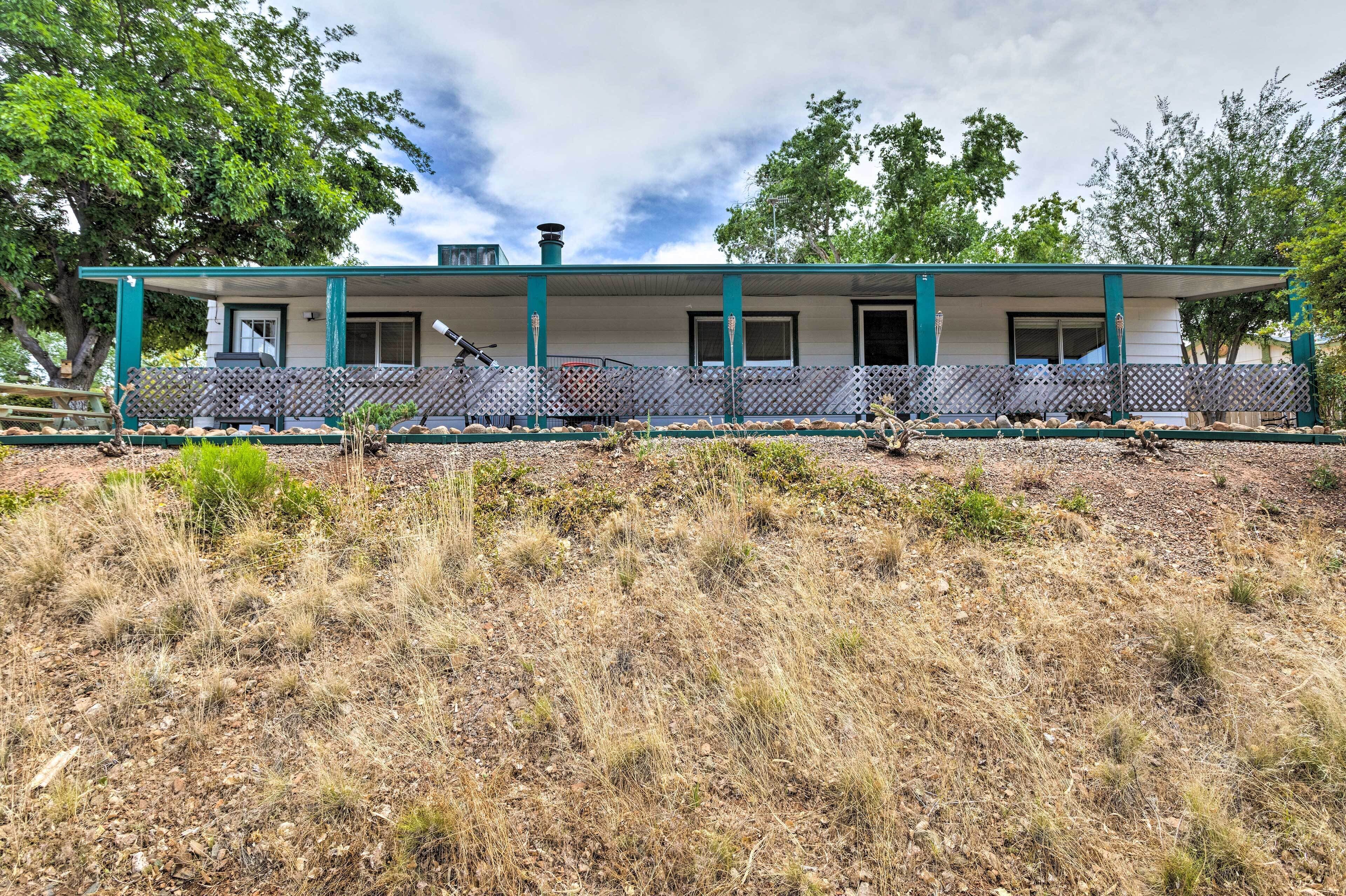 A two-story house with a covered porch, a chimney, and a fenced yard.