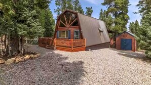 Eine Blockhütte mit einer Holzterrasse und einem kleinen Schuppen.