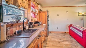 A kitchen with wooden cabinets, a sink, and a window with a view of trees. - Cozy Lake Charles Studio w/ Golf Course Views (Lake Charles)
