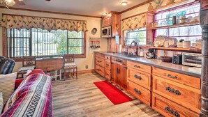A kitchen with wooden cabinets, a dining area with a table and chairs, and a red rug on the floor. - Cozy Lake Charles Studio w/ Golf Course Views (Lake Charles)